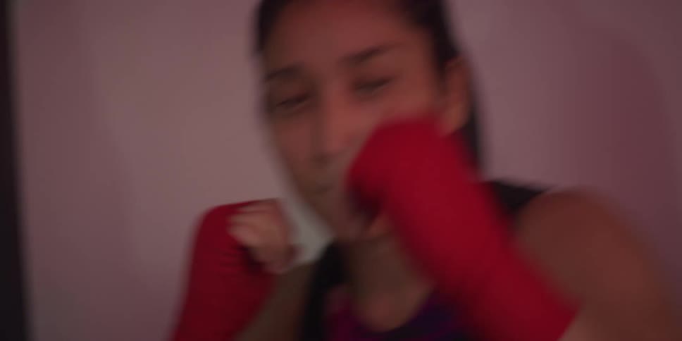 A woman is shadowboxing in the gym