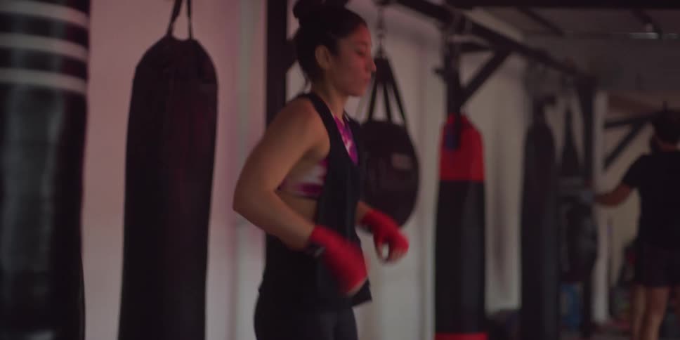Woman warming up at a martial arts gym with other people in the background