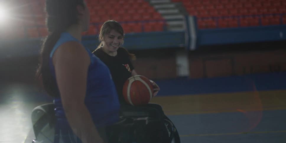 Two girls have fun playing basketball in wheelchairs