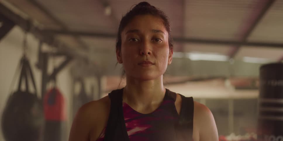 Portrait of a woman in a gym with punching bags and a focused facial expression