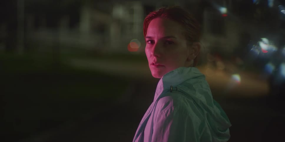 A woman with a determined look outdoors at night