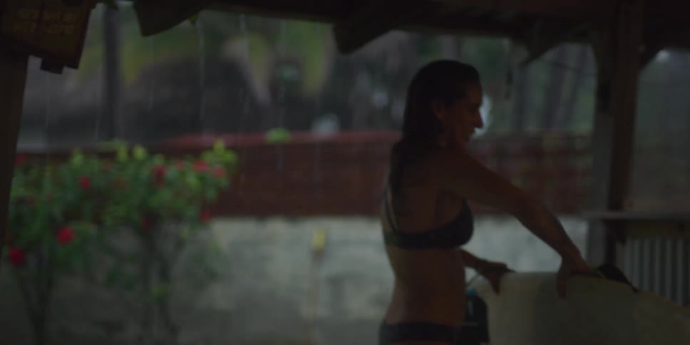 Smiling woman putting her surfboard aside and grabbing a towel to dry herself
