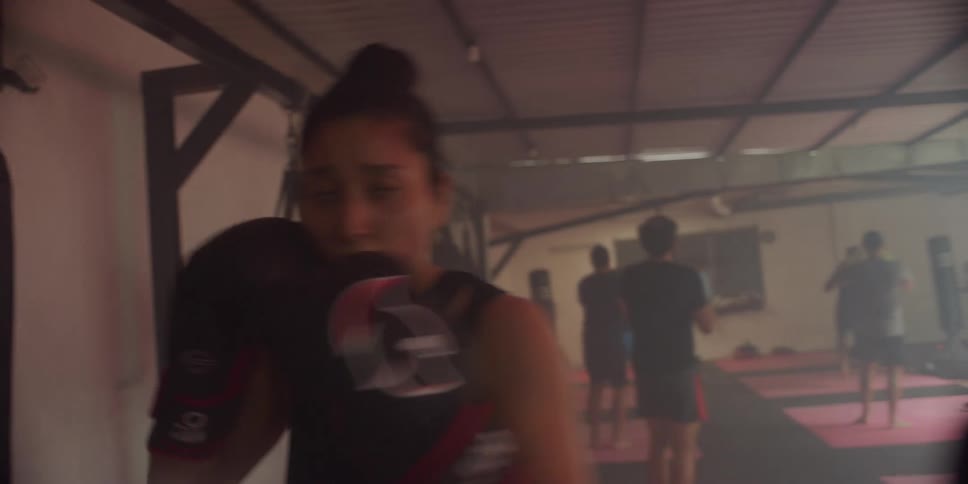 A woman wearing boxing gloves is boxing in the gym