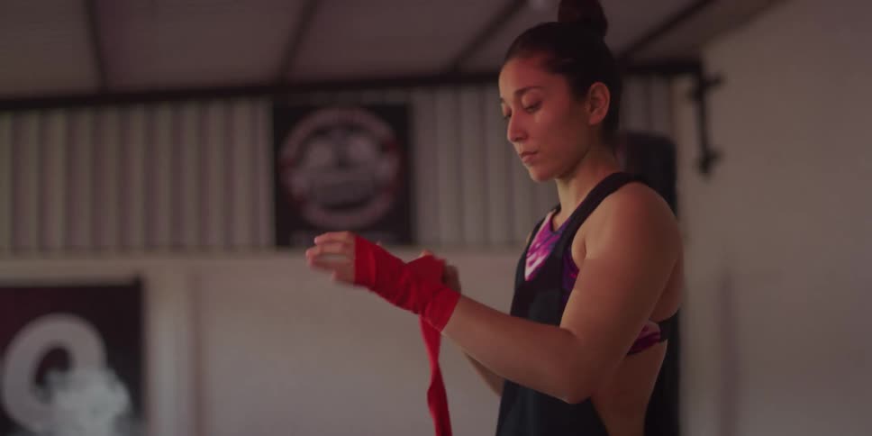 A young woman wraps her hand with red boxing wrap