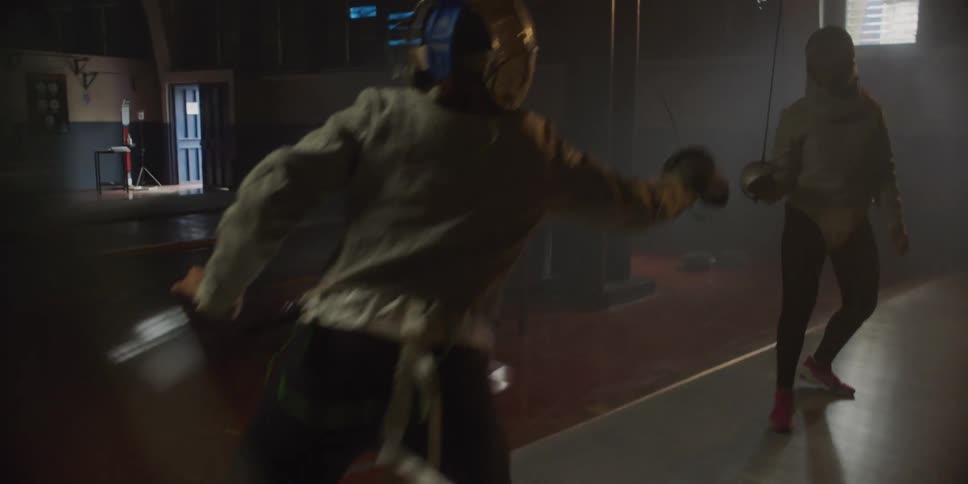 Two people are fencing on a court wearing fencing masks and clothing at midday