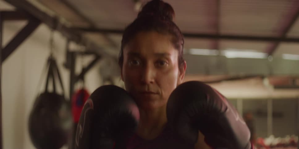 A woman jumps up and down with her boxing gloves up
