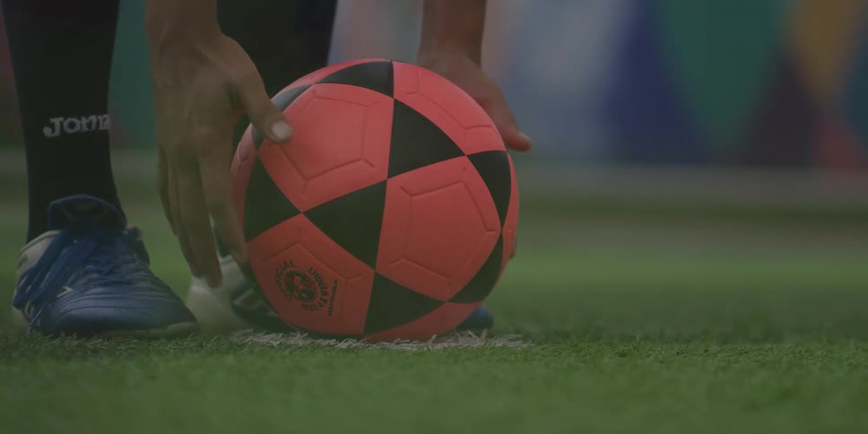 Pair of hands adjusting a soccer ball on the lawn and preparing for a foul