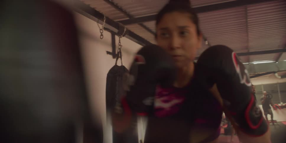 Woman training boxing by hitting the punching bag
