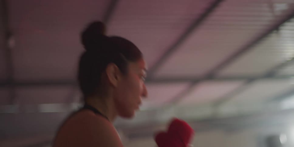 A young woman wearing red gloves is training by shadow boxing in the gym