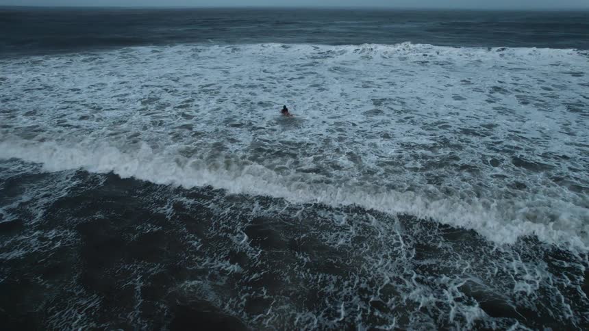 Woman with a surfboard swimming in the ocean