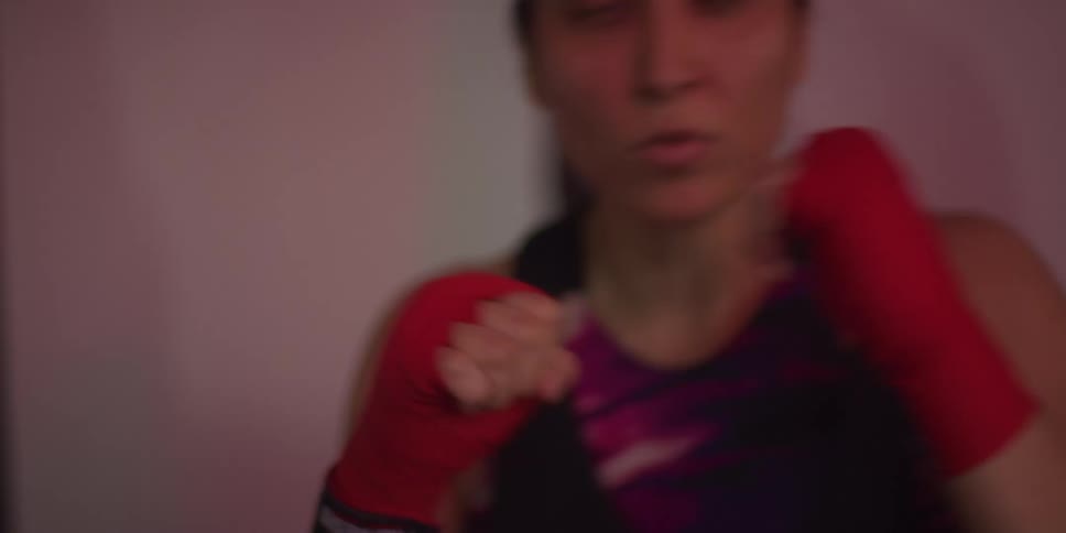 A young woman wearing red gloves is practicing boxing indoors