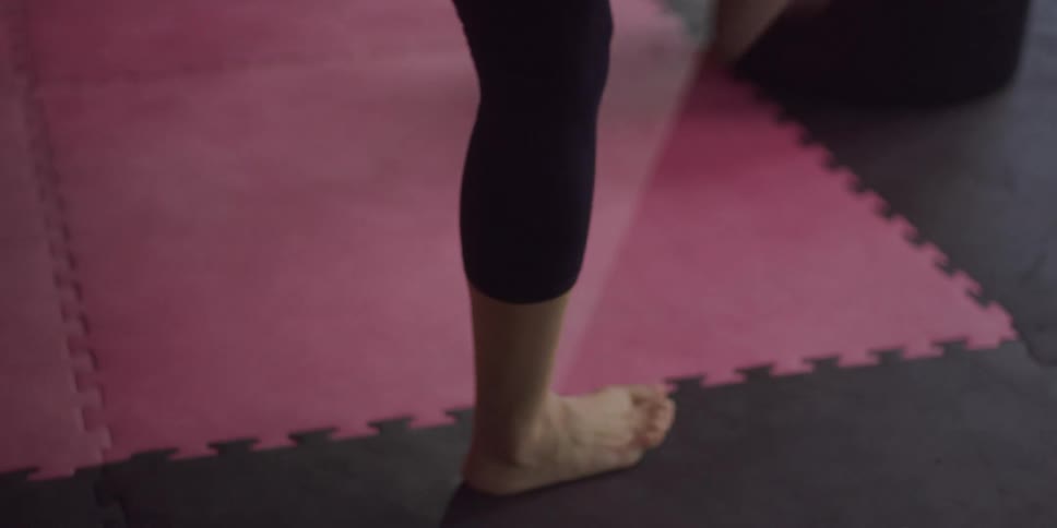 Barefoot woman in a gym practicing punches on a punching bag