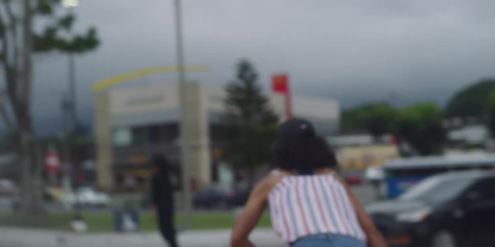 Woman in a cap skateboarding in a public square