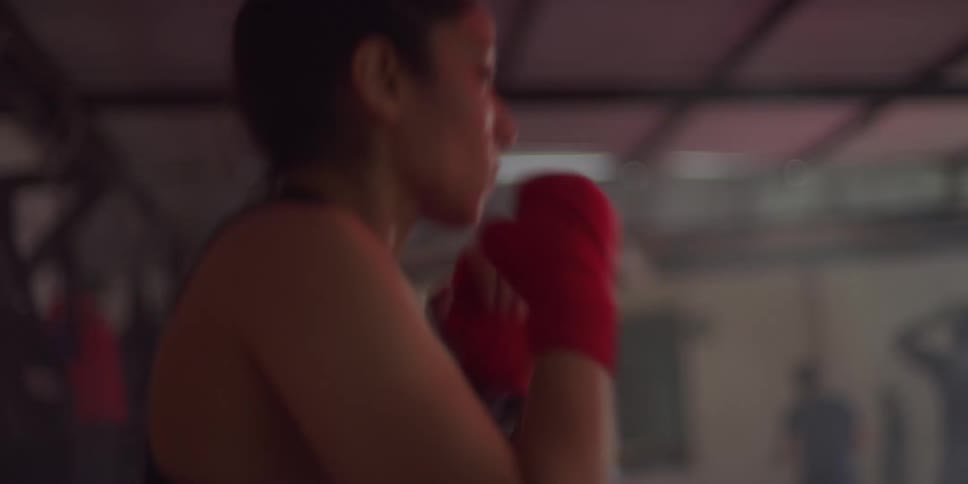 A person with red hand wraps practices punching in a gym