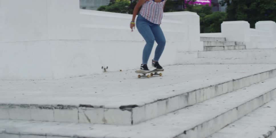 Woman doing skateboarding tricks in a square and falling
