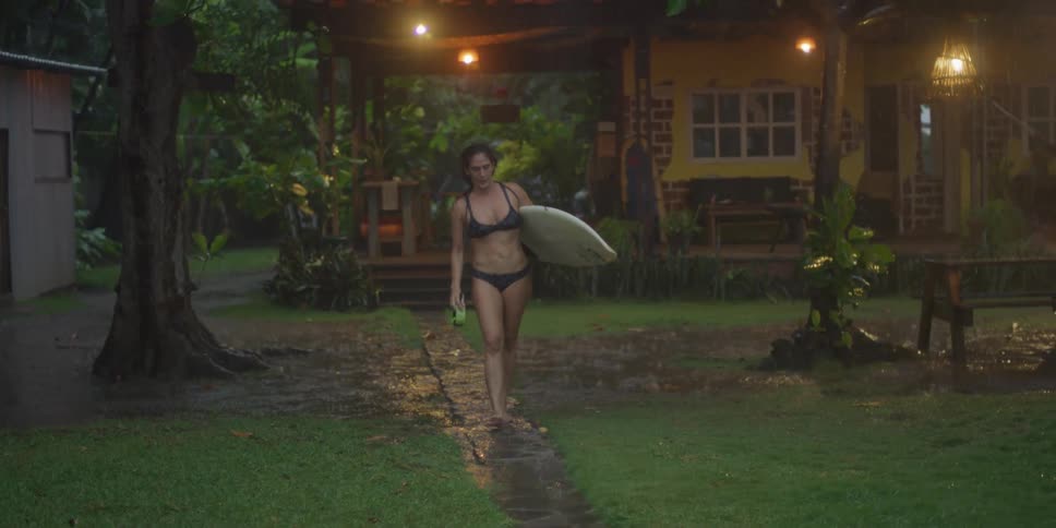 Woman walking in the rain holding a surfboard