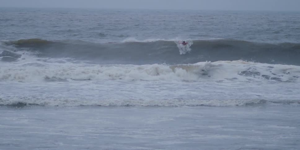 A surfer paddles vigorously to catch a breaking wave but falls behind as it crests and rolls away