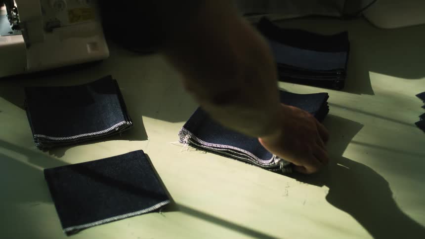 A man picking up a piece of fabric from a table