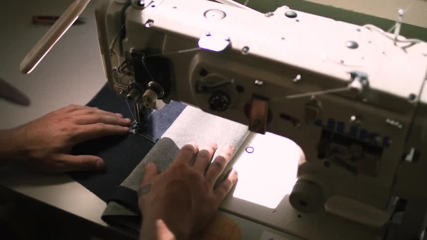 Man sews fabric with a sewing machine then gestures while planning