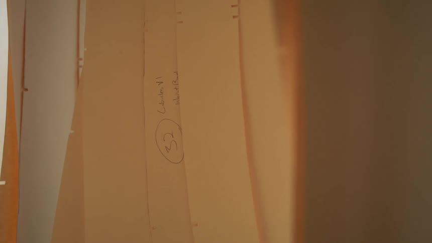 A series of yellow cardboard papers hang down swaying gently from side to side