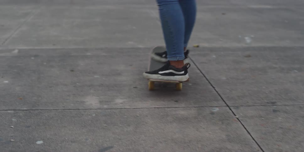 A teen woman skateboarding on a park in the city at evening