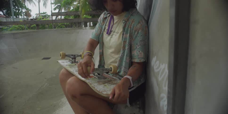 A young woman putting on her helmet and grabbing her skateboard