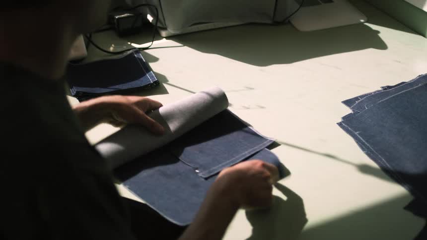 Man pins and folds fabric pieces while working on a sewing project