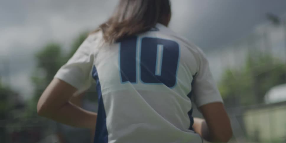 Two female football players are on the pitch at midday with one wearing a number 10 jersey as she trains by moving her feet up and down