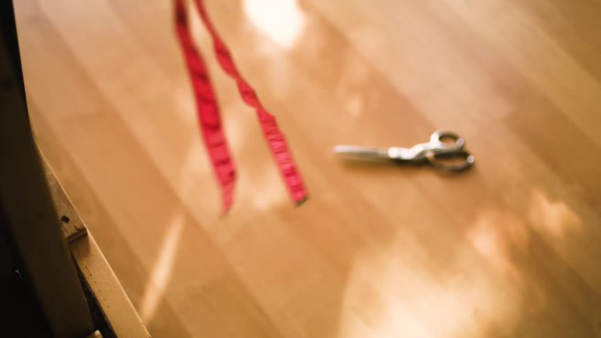 Close up of a red measuring tape and scissors in the background