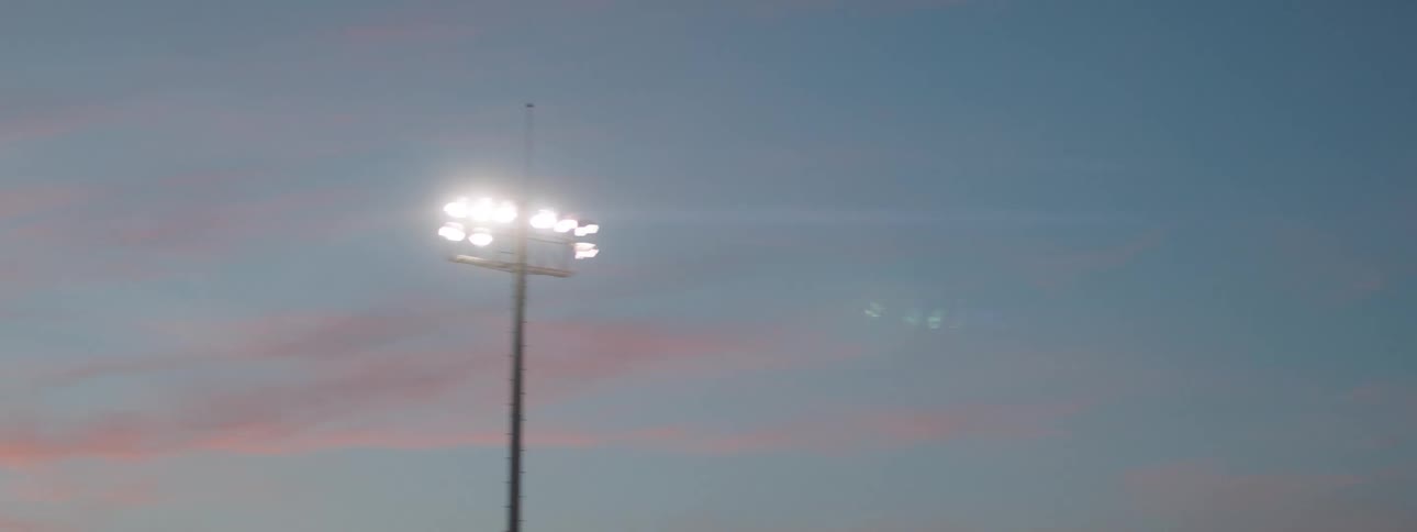 Light poles contrast with a blue sky and red tinted clouds after dusk