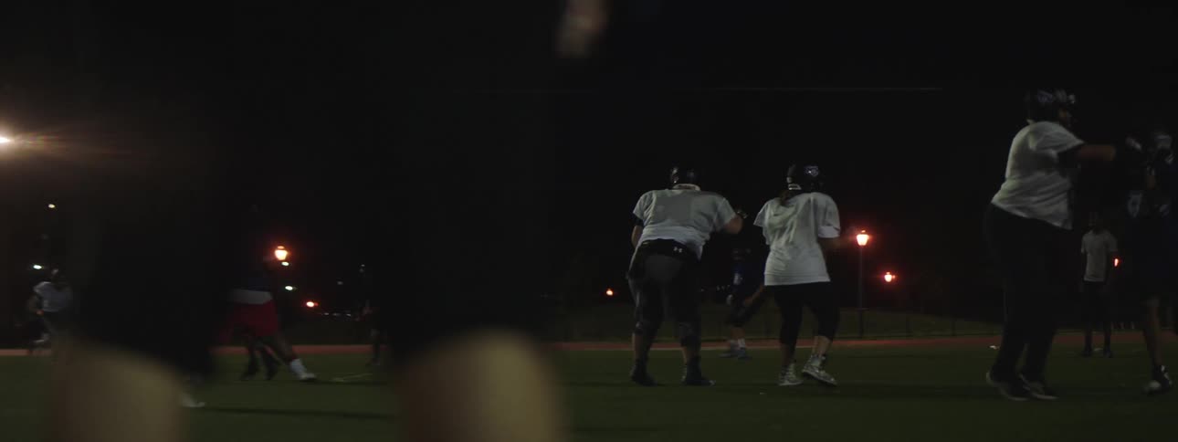 Amateur athletes play football on a football field at night