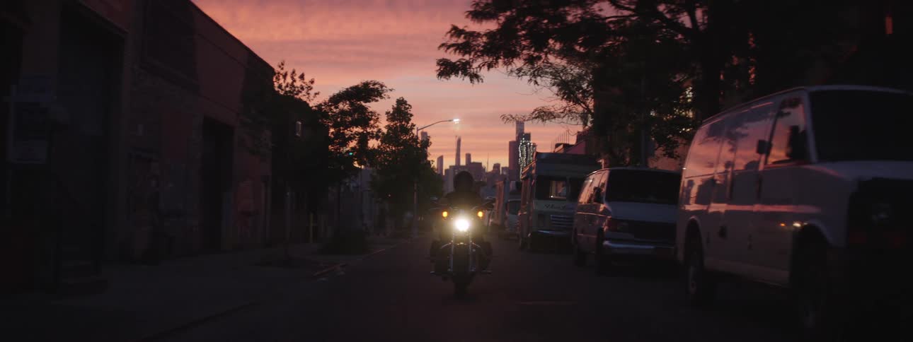 Motorcycle with headlights on moving along an urban road in the late afternoon