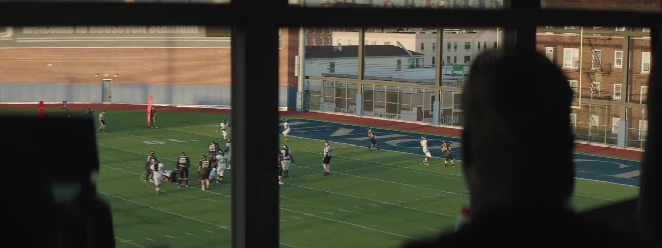 Silhouette of a person in a stadium booth watching an american football match