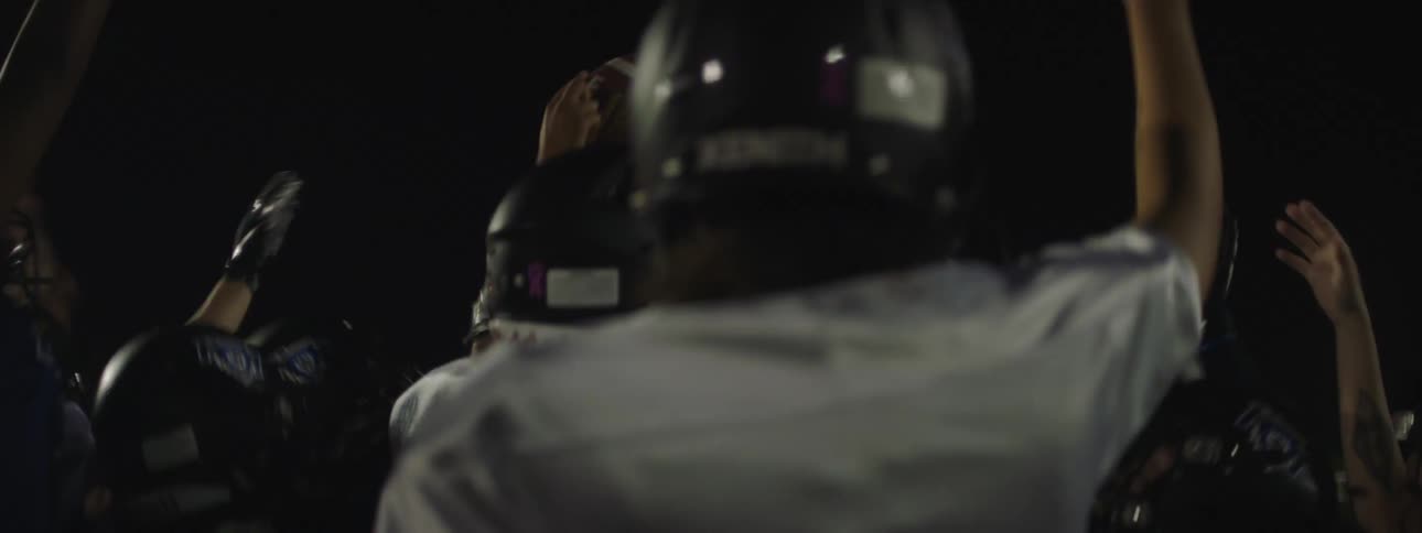 A football team is jumping and holding a football in the air while celebrating a victory