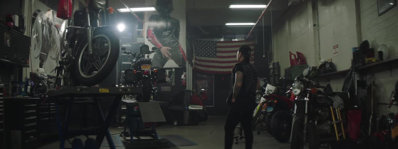 A man is standing in the shop full of motorcycles