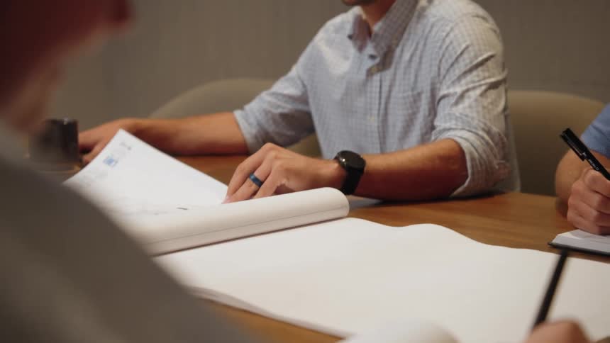 Groups of people in a meeting at an office table with a project