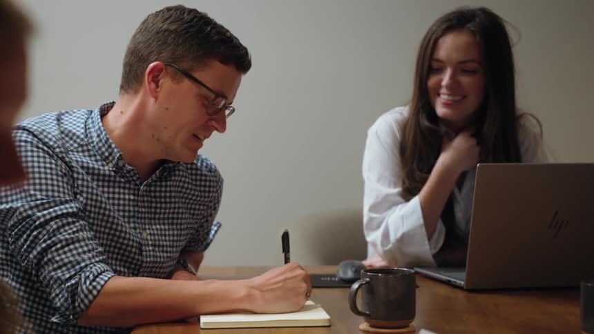 Man and two women in an office meeting sitting at a table