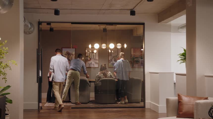 Coworkers settle into a conference room for an office meeting