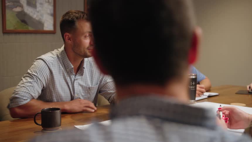 Group of people gathered around an office table discussing a project