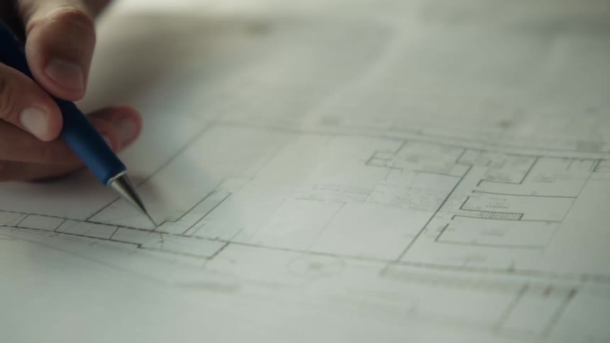 A man draws lines on the blueprints