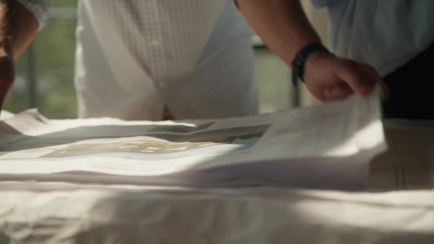 Two people analyzing an architectural plan on a table