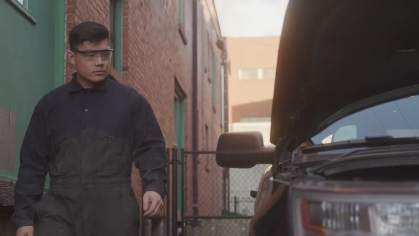 Mechanic walking next to a car with the hood open