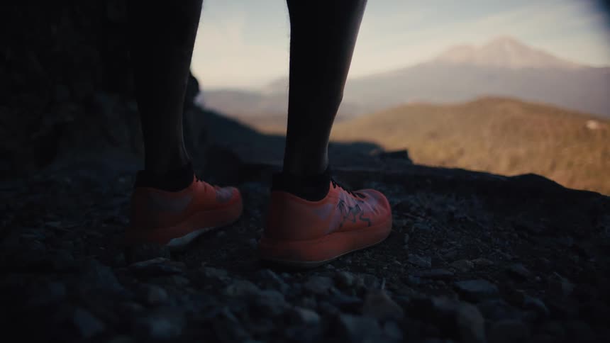 Close up of a persons legs wearing orange trail running shoes