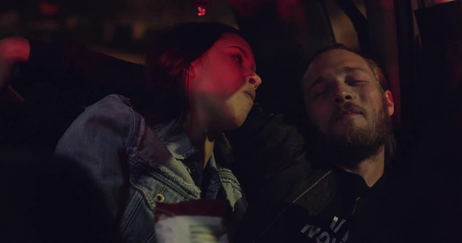 A man and woman eat in the car
