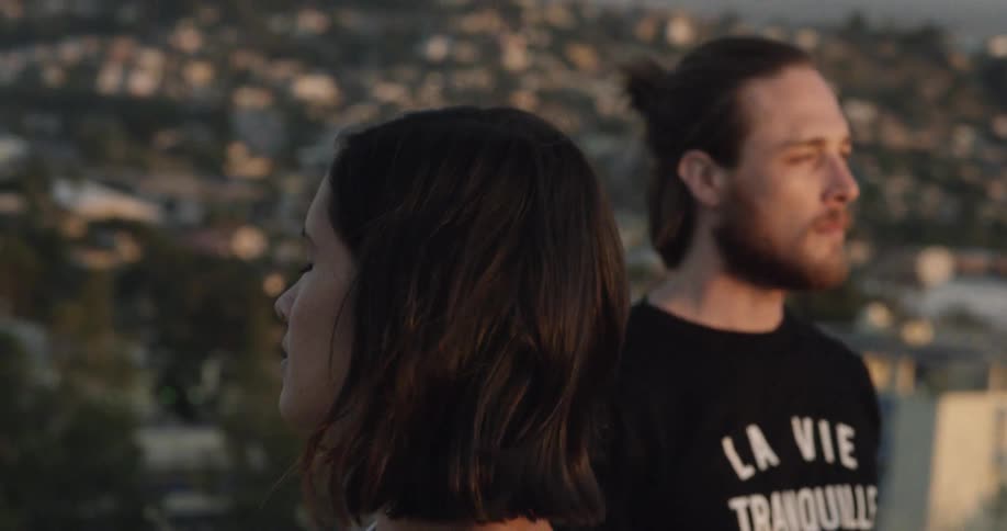 Woman and a man on a high peak overlooking a city in the late afternoon
