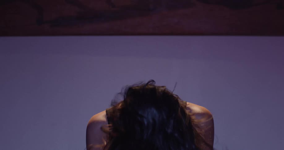 Woman laughs while headbanging in a room lit by changing colored lighting