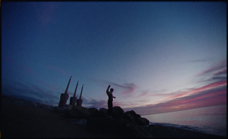 The beacons flash on the shore as the man gets dressed