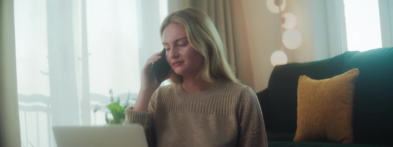 A woman talks on her cell phone by the laptop