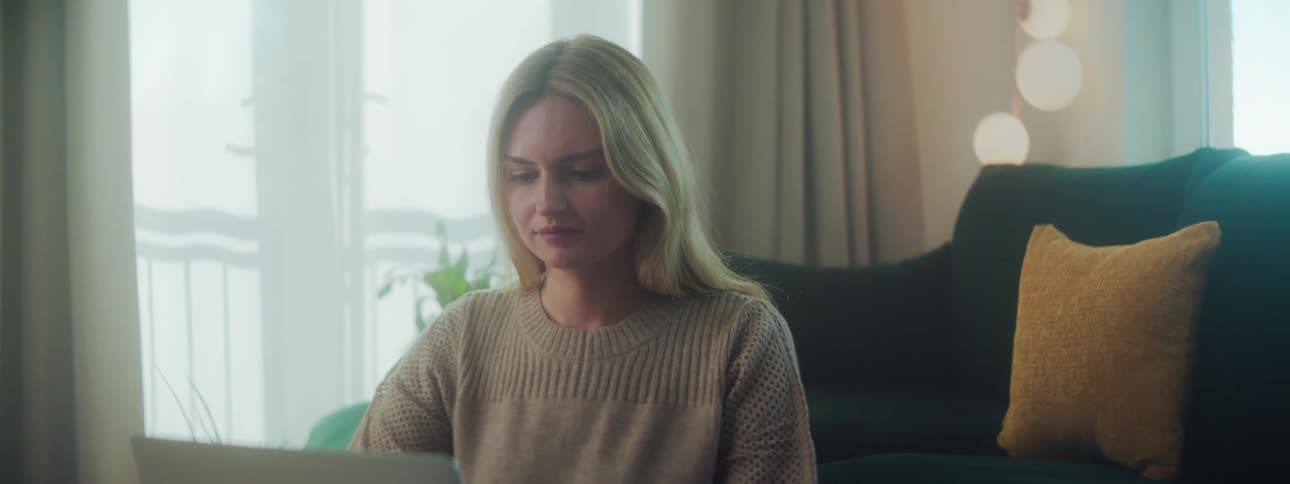Blonde woman sitting interacting with a laptop