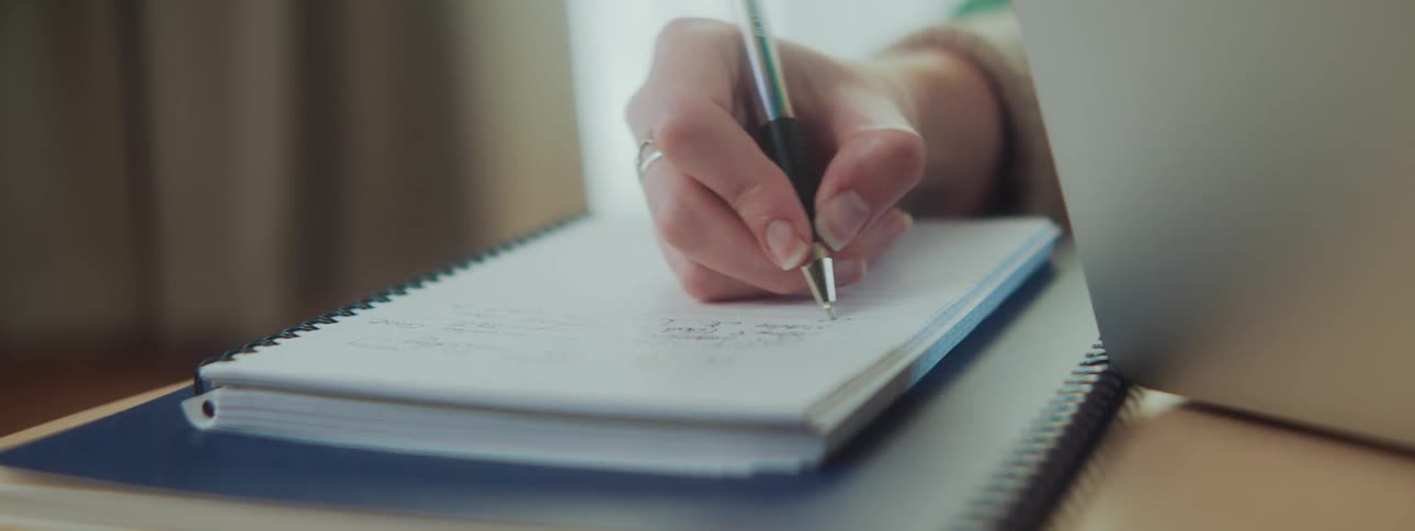 Hand with a pen writing in a notebook